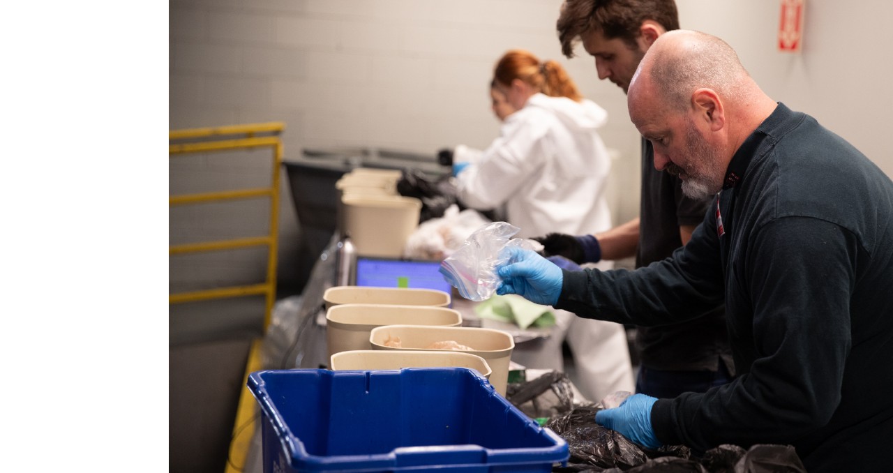 Workers sort types of waste in bins to reduce landfill waste