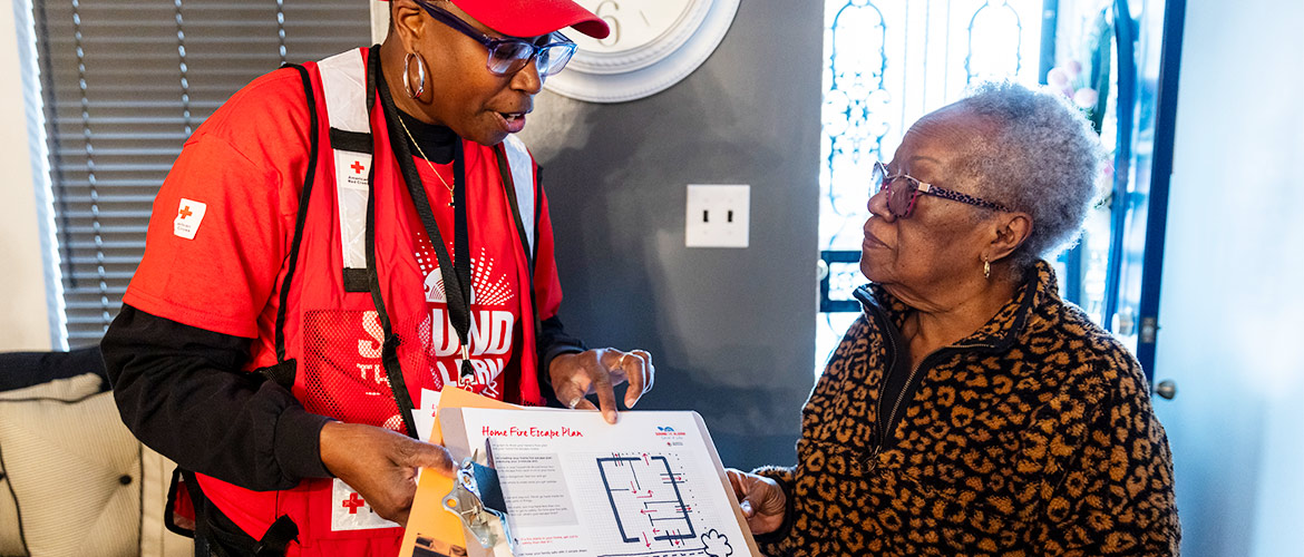 An American Red Cross volunteer explains a fire safety plan to a woman