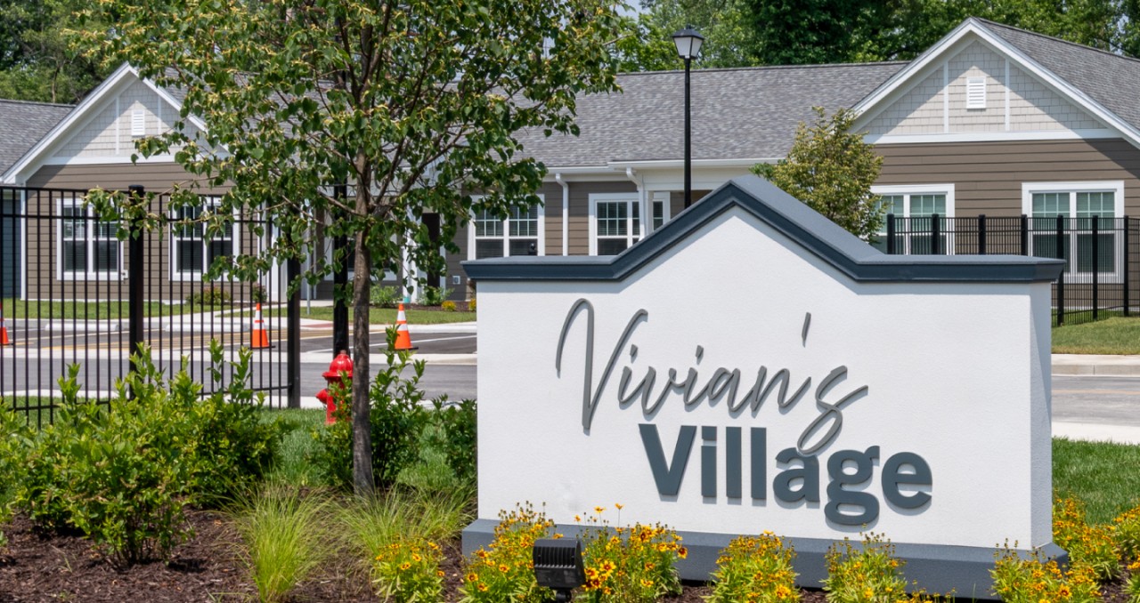 A subdivision sign reads "Vivian's Village" with newly built homes in background